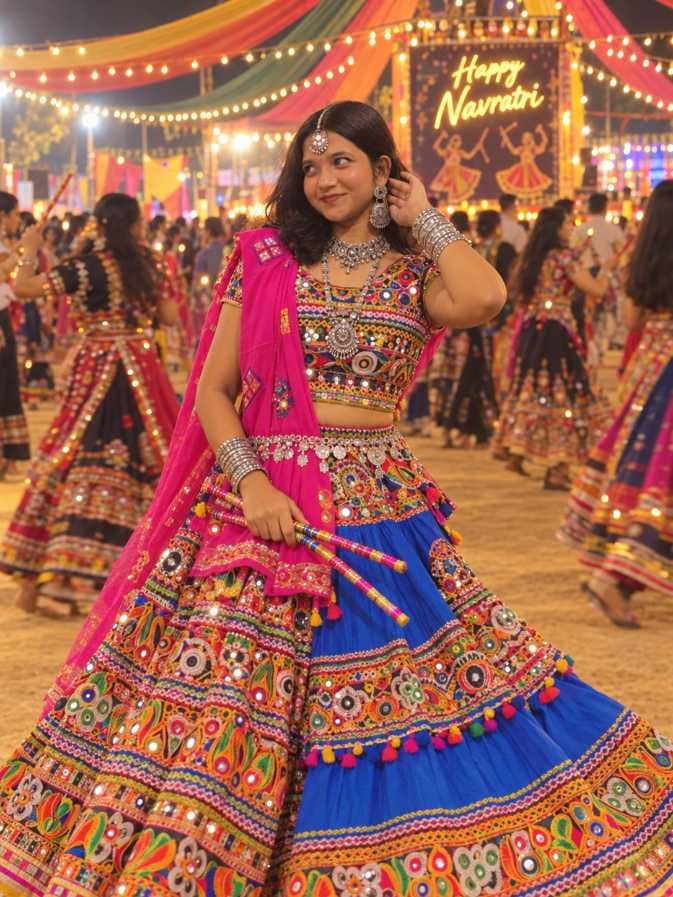 Indian girl in a blue mirror-work chaniya choli with a pink dupatta holding dandiya sticks at a Navratri ground