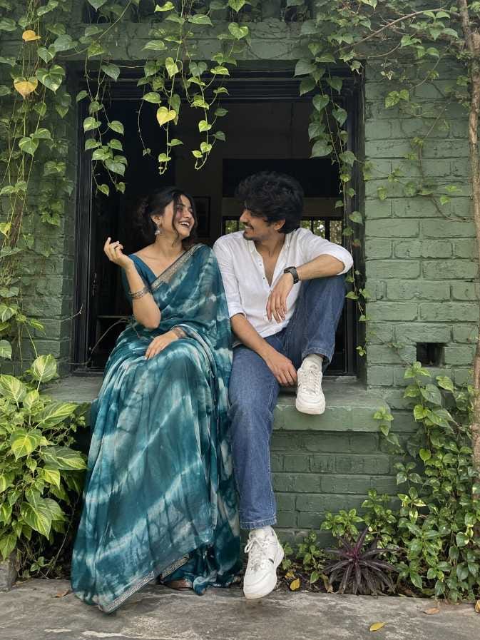 Romantic couple prompt green ledge pose, couple sitting on brick window ledge, teal tie-dye saree, gemini couple photo prompt example