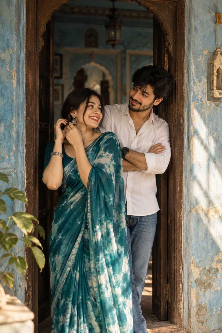 Indian couple ai photo prompt showing a couple in a heritage doorway, girl in teal tie-dye saree